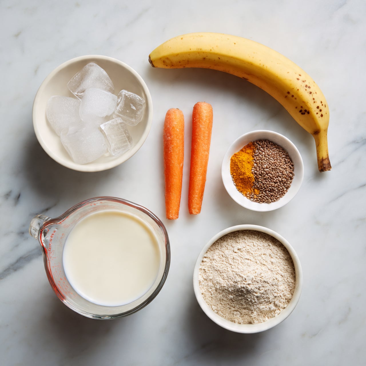 A white marbled surface holds several ingredients arranged neatly: a white bowl filled with clear ice cubes at the top left, a ripe yellow banana with brown spots placed diagonally to the right, a small white bowl of brown seeds beside the banana, two small bright orange carrots positioned just below the seeds, a clear glass measuring cup filled with white milk at the bottom left, a small amount of orange powder in a white bowl near the milk, and a white bowl containing beige flour at the bottom right. photo taken with an iphone --ar 4:5 --v 7