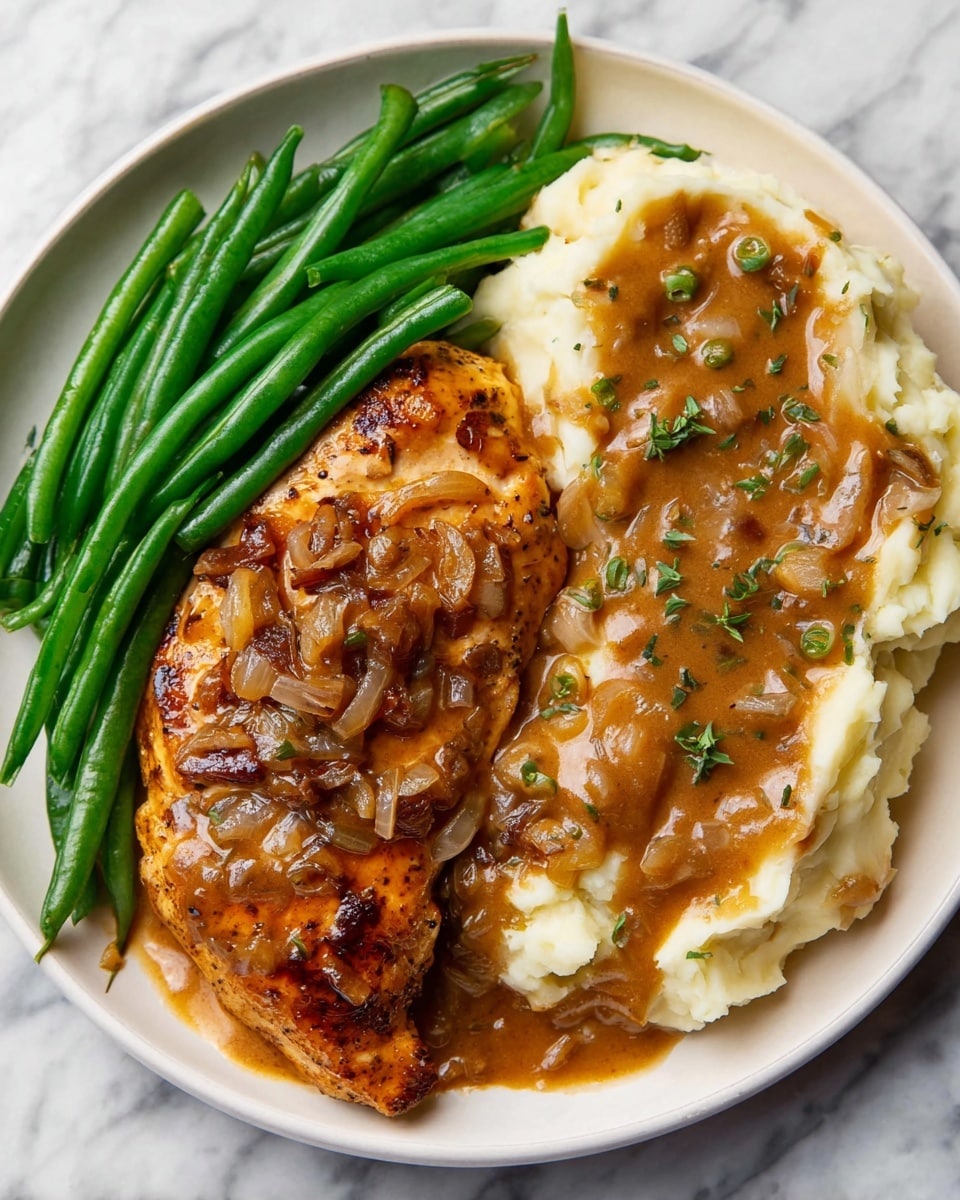 A round white plate sits on a white marbled surface, holding three main parts. On the left, there is a pile of bright green cooked green beans, smooth and shiny. In the center, a piece of grilled chicken is covered with a rich brown sauce with small bits of onions and herbs sprinkled on top, showing some grilled texture beneath. On the right side is a mound of creamy mashed potatoes, topped with the same brown sauce that spreads unevenly over the top, adding a moist texture. Small green herb bits are scattered on the sauce. The colors and textures make the dish look warm and tasty. photo taken with an iphone --ar 4:5 --v 7