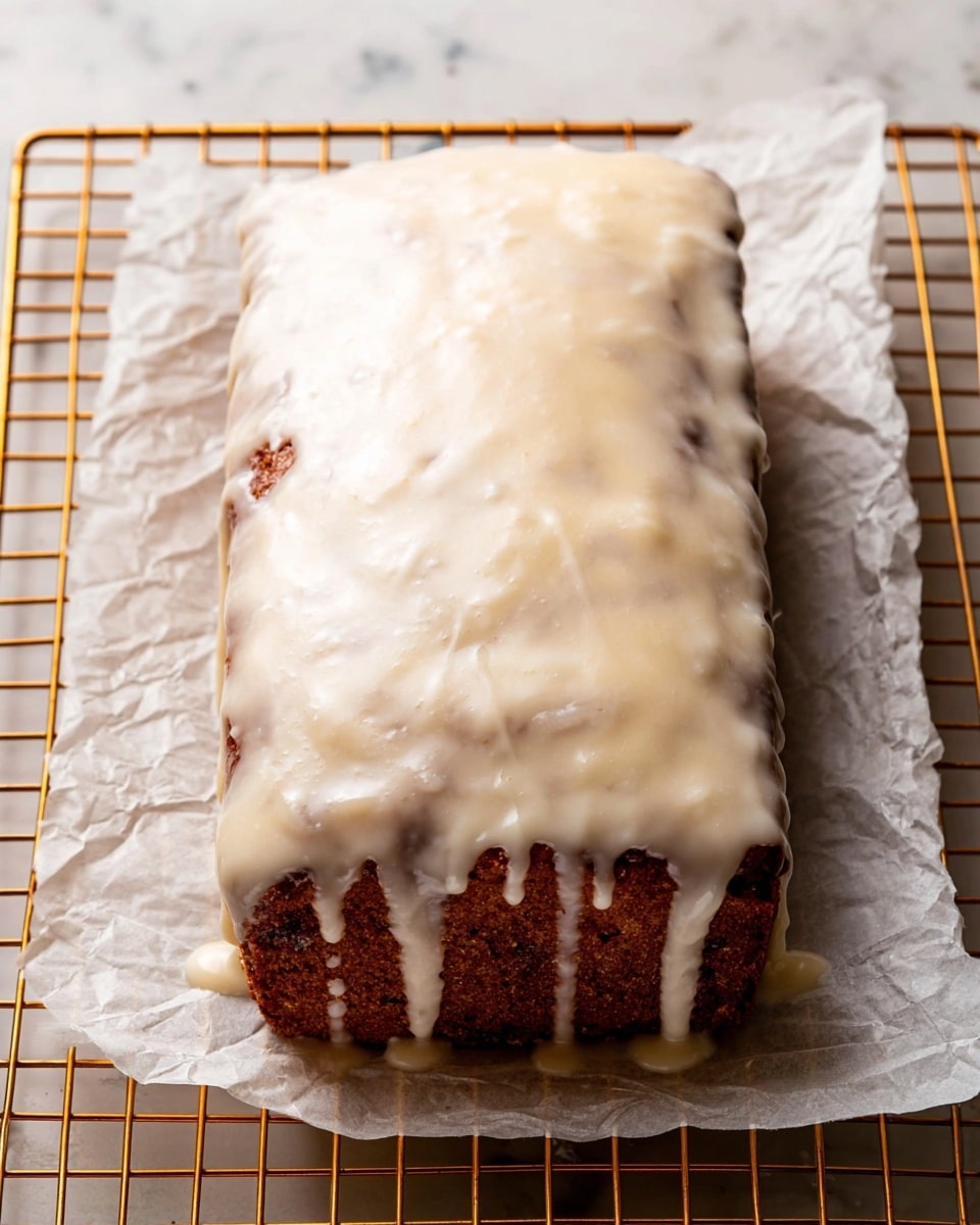 A rectangular loaf cake with a dark brown color is covered by a thick, creamy white icing that drips down the sides. The cake has a slightly rough texture visible through the smooth icing. It rests on a crinkled piece of white parchment paper, which is placed on a golden cooling rack set against a white marbled surface. The icing has a slightly glossy finish and an uneven spread, showing some of the cake beneath in certain spots photo taken with an iphone --ar 4:5 --v 7