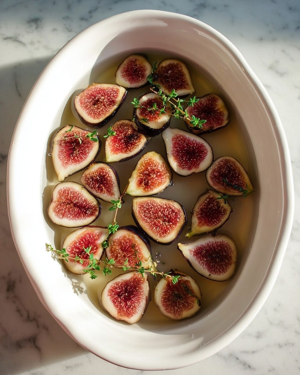 A white oval dish filled with thin water, containing about twenty fig halves arranged in one layer. Each fig half shows a deep pink center with light seeds, surrounded by dark purple skin. Small green herb sprigs float on top of the figs, adding fresh green touches. The dish is placed on a white marbled surface and the lighting is soft and natural. photo taken with an iphone --ar 4:5 --v 7