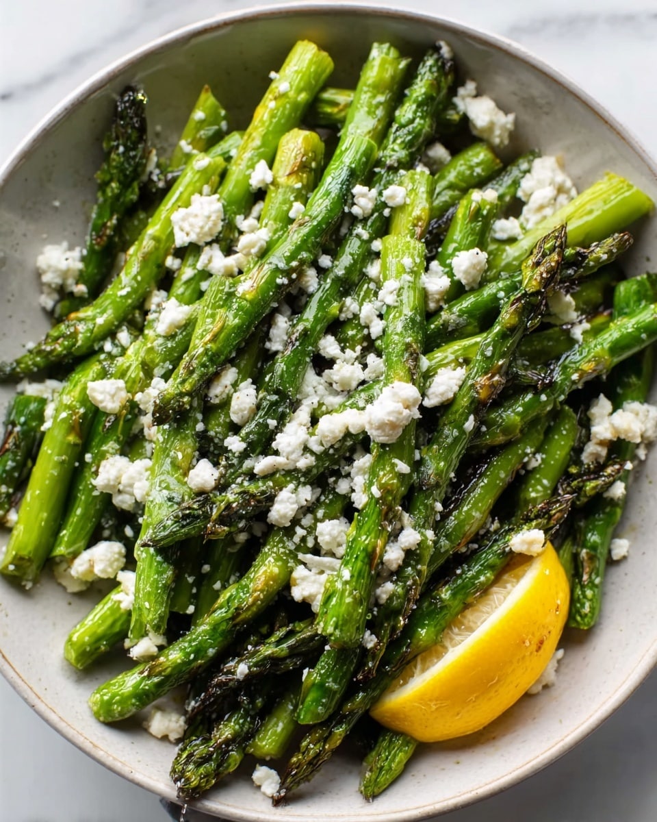 Grilled asparagus spears topped with crumbled feta and a lemon wedge.