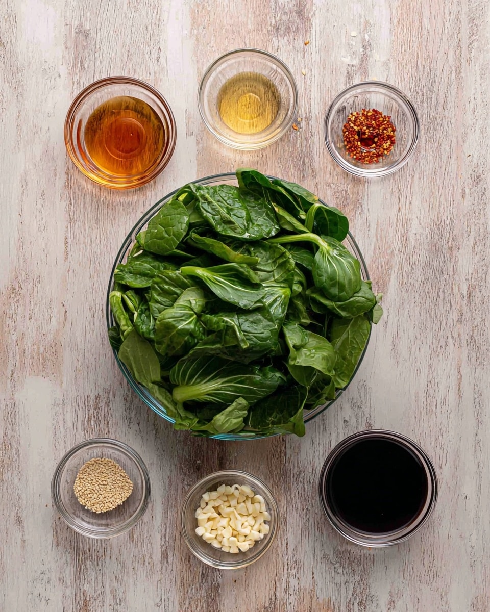 A clear glass bowl filled with fresh, dark green leafy bok choy sits at the bottom center of the image on a white marbled surface. Above it, five small clear glass bowls hold various ingredients: from left to right, a light amber liquid, a light clear liquid, a dark brown soy sauce, white sesame seeds, red chili flakes, and finely chopped garlic. The ingredients are neatly arranged in a line directly above the bowl of bok choy. Photo taken with an iphone --ar 4:5 --v 7