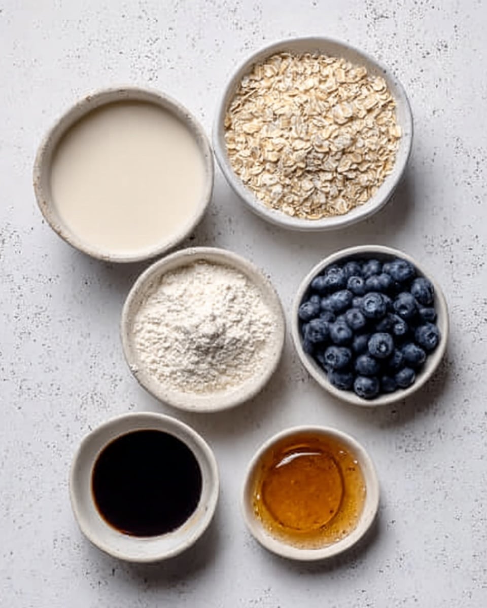 The image shows six small white bowls arranged in a neat, scattered pattern on a white marbled surface. One bowl contains a smooth, off-white creamy liquid. Another bowl is filled with light beige rolled oats, creating a rough texture layer. A third bowl has fine white flour with a powdery texture. A fourth bowl holds fresh, round blueberries that are deep blue with a slightly shiny surface. The fifth bowl has a dark brown liquid, likely vanilla extract, appearing glossy and smooth. The sixth bowl contains a golden brown syrup with a shiny, thick texture. Photo taken with an iphone --ar 4:5 --v 7