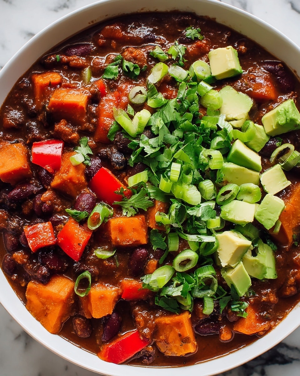 This image shows one bowl filled with a thick, hearty chili with many layers of colorful ingredients. On the bottom layer, there is a rich, dark brown sauce filled with chunks of orange sweet potatoes, red bell peppers, black beans, and kidney beans. On top, there is a fresh layer of chopped green onions and bright green avocado cubes, along with chopped fresh cilantro scattered around. The bowl is white, sitting on a white marbled surface, and the food looks warm and inviting with a mix of soft and chunky textures. photo taken with an iphone --ar 4:5 --v 7