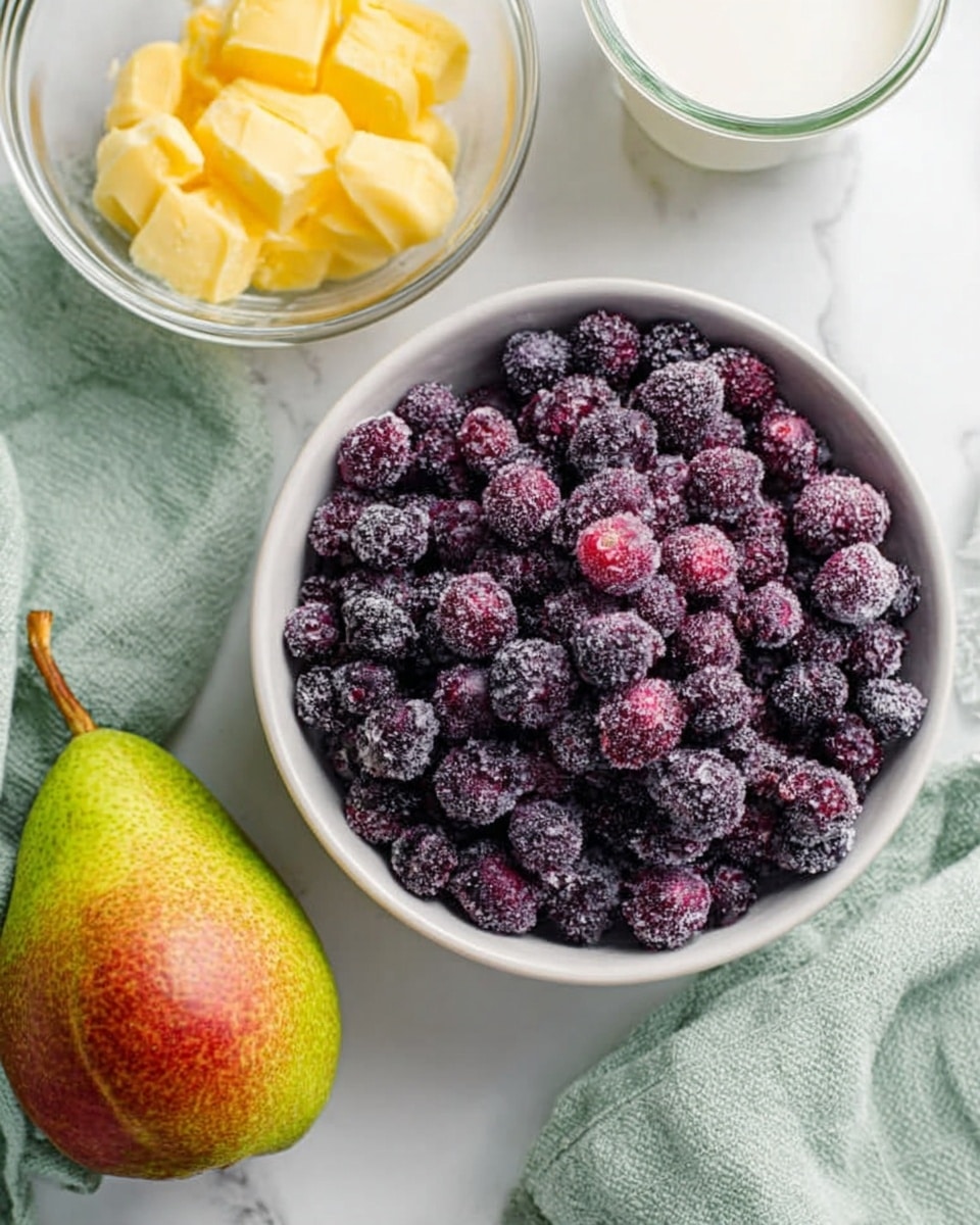 The image shows a white bowl full of small, dark purple berries with a frosty look, placed on a white marbled surface. Next to the bowl, there is a whole pear with green and red skin sitting on the surface. Above the pear, there is a clear glass bowl with yellow butter inside. On the right side, a small glass container holds white milk. A soft green cloth is in the background. The scene is bright and clear, with simple natural colors. Photo taken with an iphone --ar 4:5 --v 7