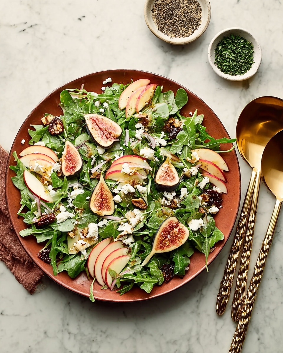 A white plate is filled with multiple layers of fresh green arugula leaves creating a leafy base, topped with thin red and yellow apple slices arranged evenly across, beside halved figs showing soft pink interiors with tiny seeds. White crumbly cheese is sprinkled generously on top, with a few dark brown candied nuts scattered around, adding texture. The salad is garnished with small chopped bits of light pink shallots and chives, with a light drizzle of dressing adding a slight shine. To the right, golden salad serving spoons with twisted handles rest on the white marbled surface, while two small white bowls holding black and green chopped seasonings add color contrast nearby. photo taken with an iphone --ar 4:5 --v 7