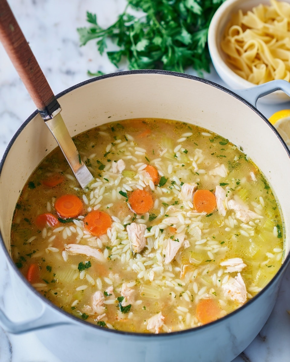 A white pot filled with a soup showing three main layers: a clear, light yellow broth at the base with a slightly oily texture, small pieces of light pink chicken scattered throughout, and orange carrot slices evenly spread on top. There are also small white pasta pieces shaped like rice grains mixed well within the soup. Light green herbs and thin celery pieces float gently across the surface. A knife with a brown handle is placed vertically inside the pot. In the background, there is a bowl of uncooked pasta, a yellow lemon, and some green parsley on a white marbled surface. Photo taken with an iphone --ar 4:5 --v 7